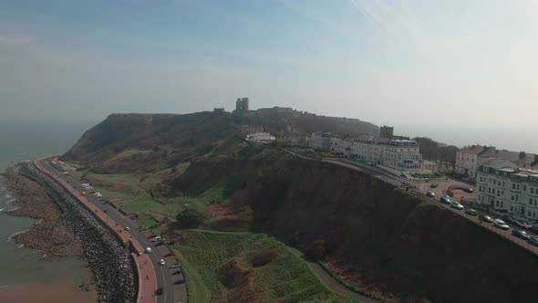 Aerial view along Scarborough coastline towards medieval castle landmark ruins hillside viewpoint