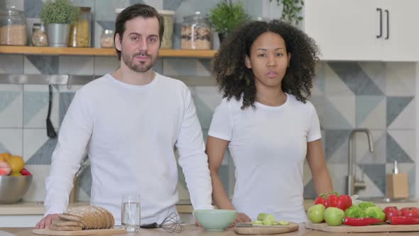 Mixed Race Couple Looking at Camera in Kitchen