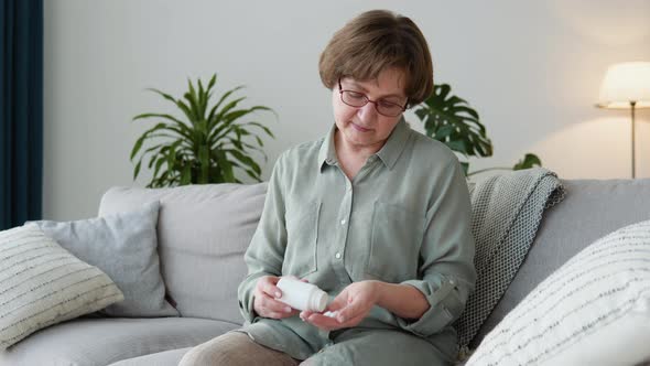 Senior Adult Woman Holding Painkiller Pills on Female Hand Pouring Capsules From Medical Bottle