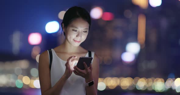 Woman checking on mobile phone in city at night