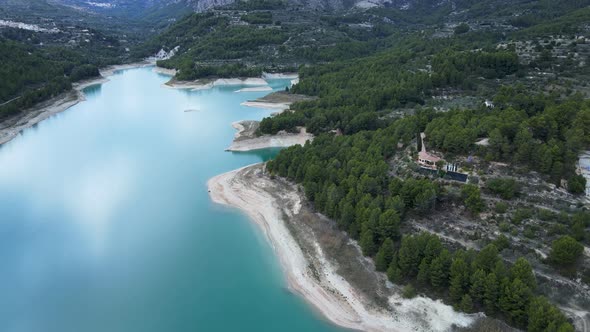 Aerial of Lake Forest Mountains and Buildings By Shore in Guadalest