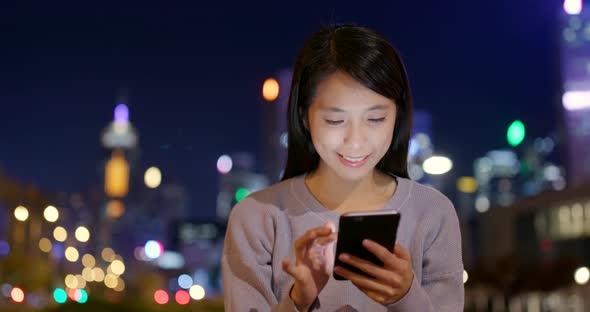Young Woman use of mobile phone in city at night