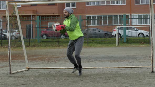 Middle Eastern Goalkeeper Catching Soccer Ball while Playing Outdoors