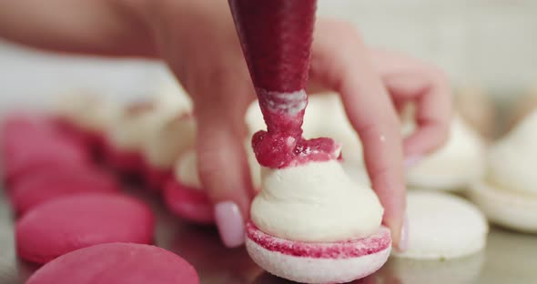 Beautiful Pink Macaroons Fill with Pink Jam on a Pink Background