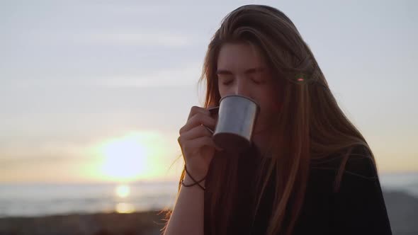 Closeup Beautiful Long Haired Woman Cautiously Drinking Hot Coffeee From Metal Cup on Nature Early