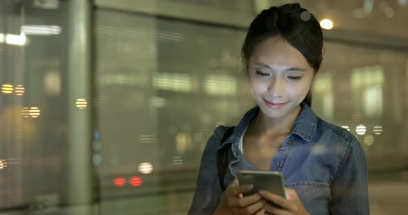 Young woman working on mobile phone at night 