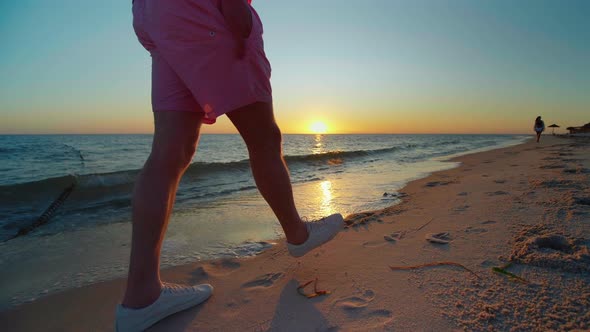 Man walking on the beach at the sunset