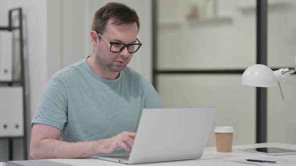 Thumbs Up By Young Man with Laptop at Work