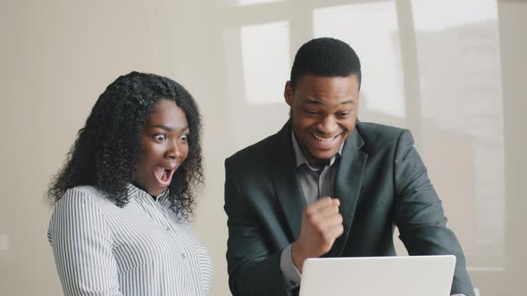 Excited Young Multiethnic African American Colleagues in Formal Wear Happy Looking at Laptop Screen