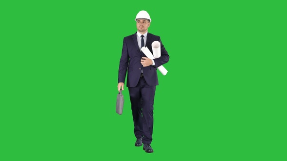 Male architect in a suit and hard hat walking with blueprints