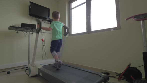 Little Boy Slowly Walks on the Medical Treadmill