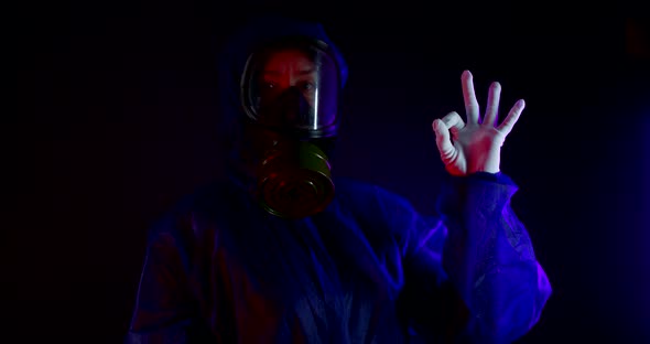 Portrait of a Woman in a Protective Suit, White Gloves and a Gas Mask on a Black Background