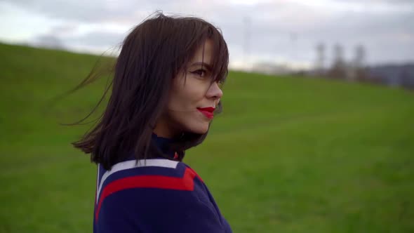 Portrait of a Dark-haired Young Pretty Girl Walking on the Street on the Grass, She Has Bright