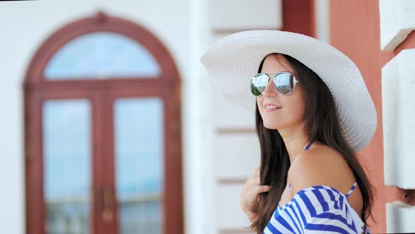 Portrait of Pretty Young Woman in Sunglasses and Hat Playing with Her Hair Smiling and Flirting