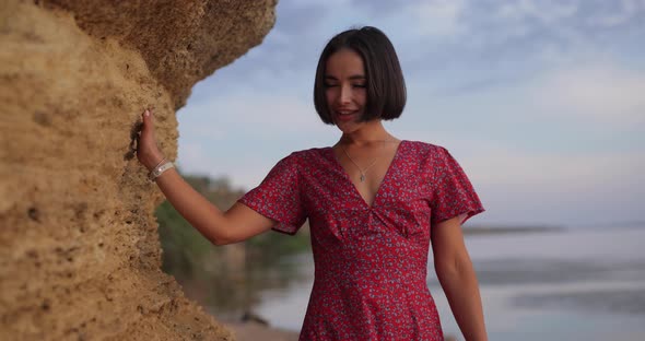 Pretty Woman in Summer Dress Near Big Stone on the Beach