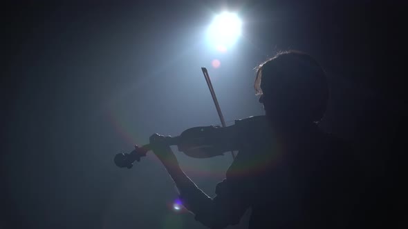 Girls Standing Back and Playing on Violins in a Dark Room