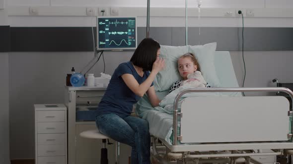 Worried Mother Sitting Beside Sick Daughter During Sickness Examination in Hospital Ward