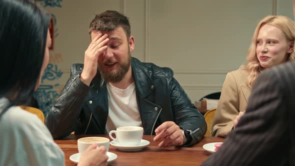 Handsome stylish guy drinks filter coffee in a coffee shop in the company of cheerful friends.