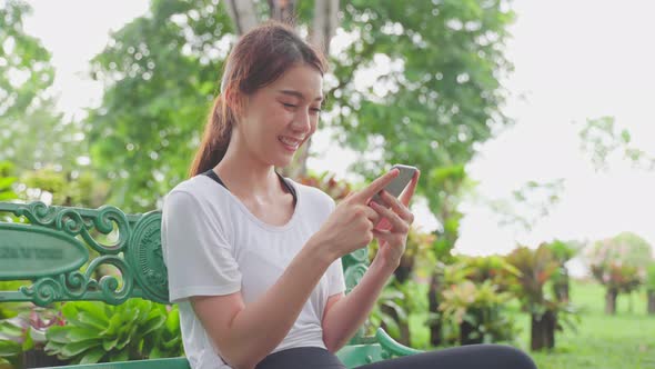 Asian woman enjoy communicate talking on mobile phone in public park.