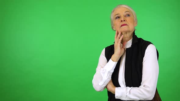 An elderly woman thinks about something - green screen studio