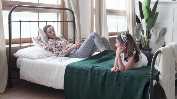 Two women are lying on the bed in the room.