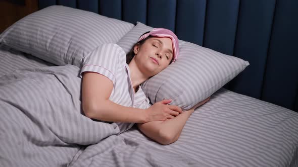 Woman in a Pink Eye Mask Lies Under a Blanket in a Bed and Suffers From Insomnia