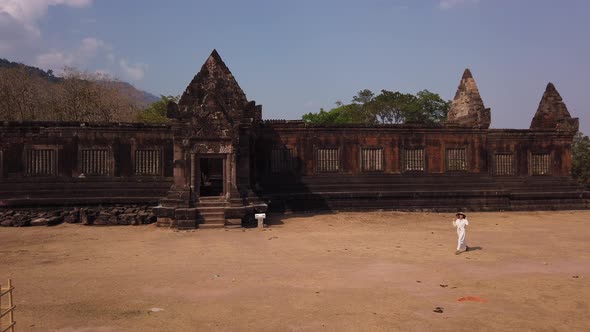 Woman in vietnamese hat walk near ancient Khmer palace Vat Phou ruined Hindu Temple Laos, Asia, Slow