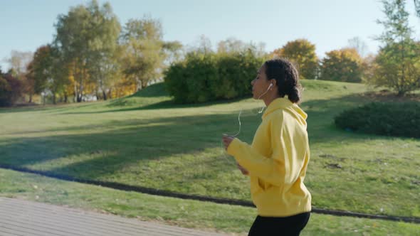 Girl Running on Track at the City Park in Sunny Autumn Morning Using Headphones