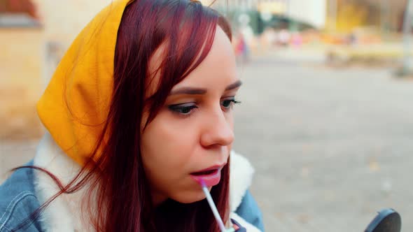 Young Woman Paints Her Lips of Lipstick Outdoors