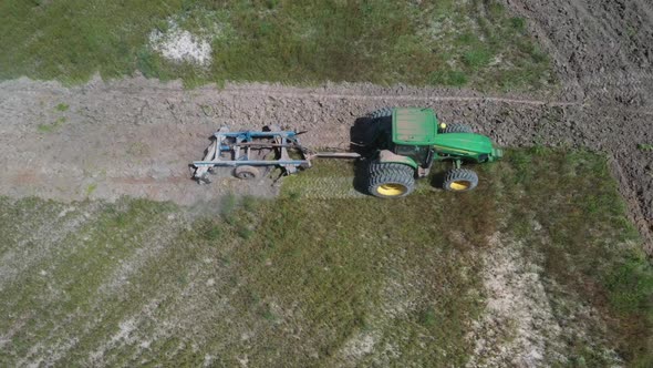 A tractor plowing a field in Brazil on land deforested from the Amazon rainforest - aerial view