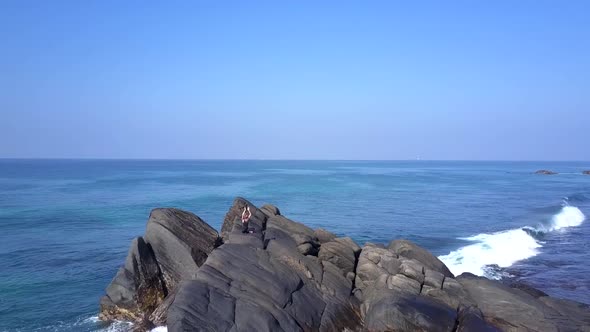 Girl Practices Yoga on Cliff at Foaming Ocean Waves