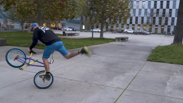 Guy riding a BMX bike in a skatepark, performing the Steamroller trick.