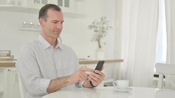 Attractive Middle Aged Man Using Smartphone at Home 