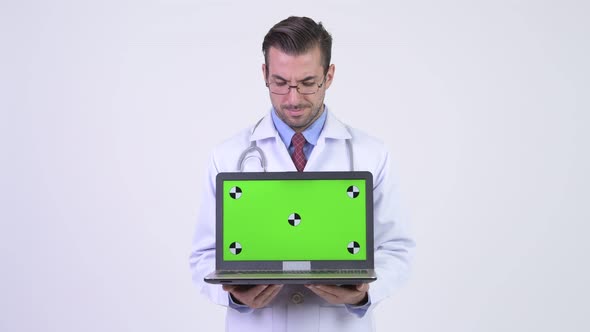 Young Happy Hispanic Man Doctor Thinking While Showing Laptop