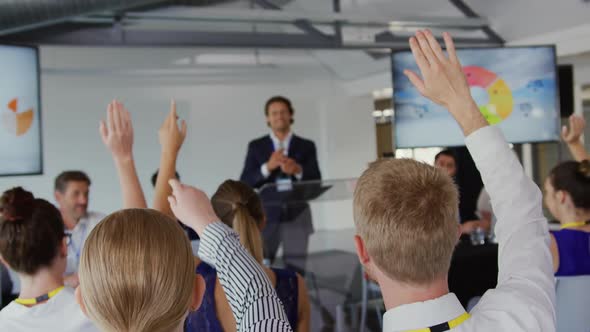 Businessman inviting questions from the audience at a business conference