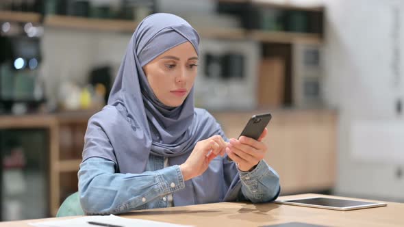 Unhappy Arab Woman with Loss on Smartphone in Cafe