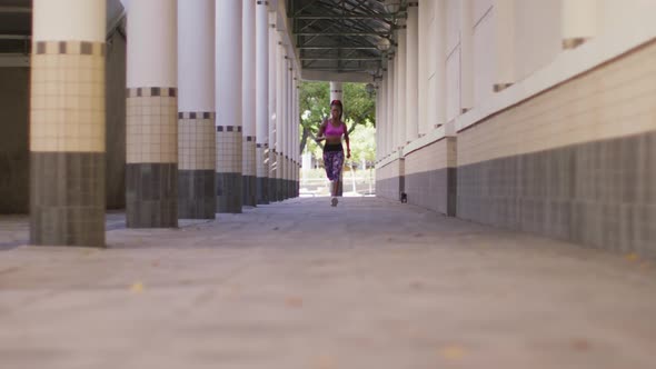 African american woman wearing earphones running in the corridor