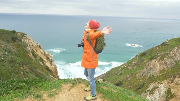 Tourist with Camera Turns on Hilly Coast Against Ocean