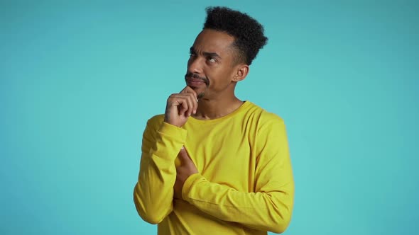 Thinking African Man Looking up And Around on Blue Background. Worried Contemplative Face