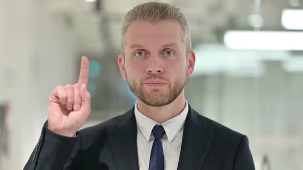 Portrait of Serious Young Businessman Saying No By Finger Sign