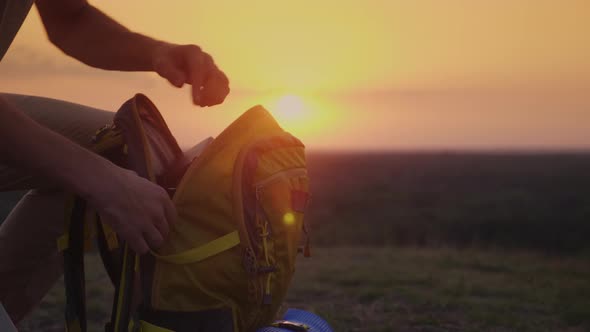 A Man Is Packing His Backpack at Sunset. Preparing for a Trip or Trekking