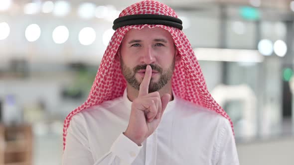 Serious Arab Businessman Putting Finger on Lips 