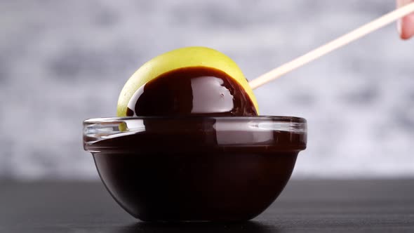 Crop Person Dipping Apple in Chocolate Sauce