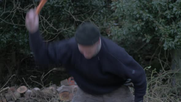 Driven man chopping logs within wilderness