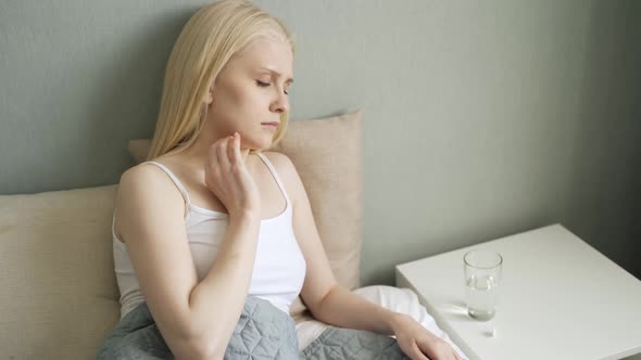 Unhappy Woman Taking a Pills and Drinking Glass of Water