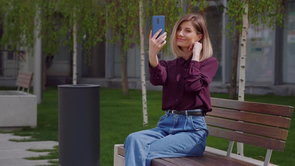 Pretty woman taking selfie photo on smartphone in park city