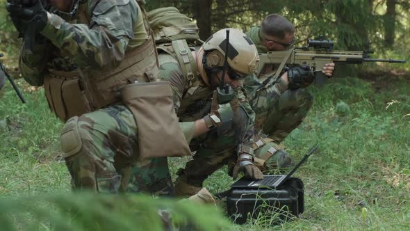 Special Forces Soldiers Using Laptop In Jungle alt