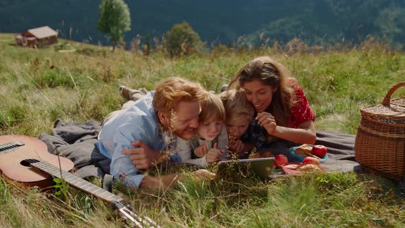 Family Holding Tablet Picnic Lying Grass Mountain Hill