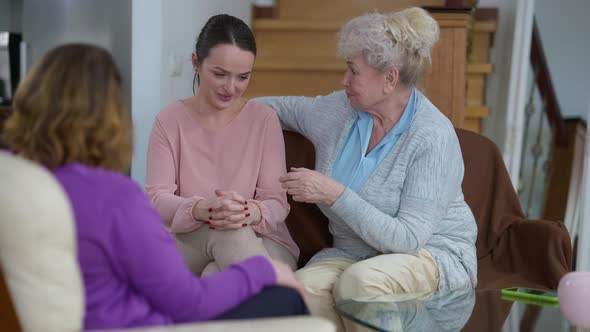 Young Troubled Woman Crying As Wise Senior Grandmother and Adult Mother Calming Down Sad Beautiful