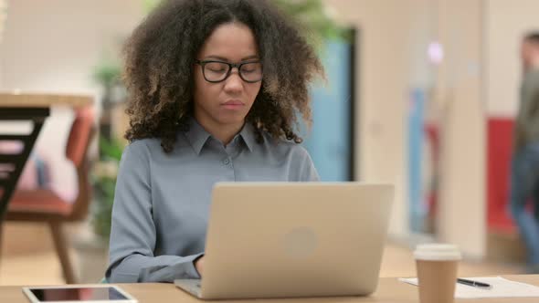 Young African Woman with Laptop Looking at Camera